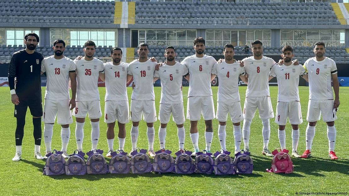 Jogadores posam em campo em frente a mochilas infantis