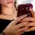 A teenage girl on her mobile phone. She is only seen from below the nose, hiding her identity.