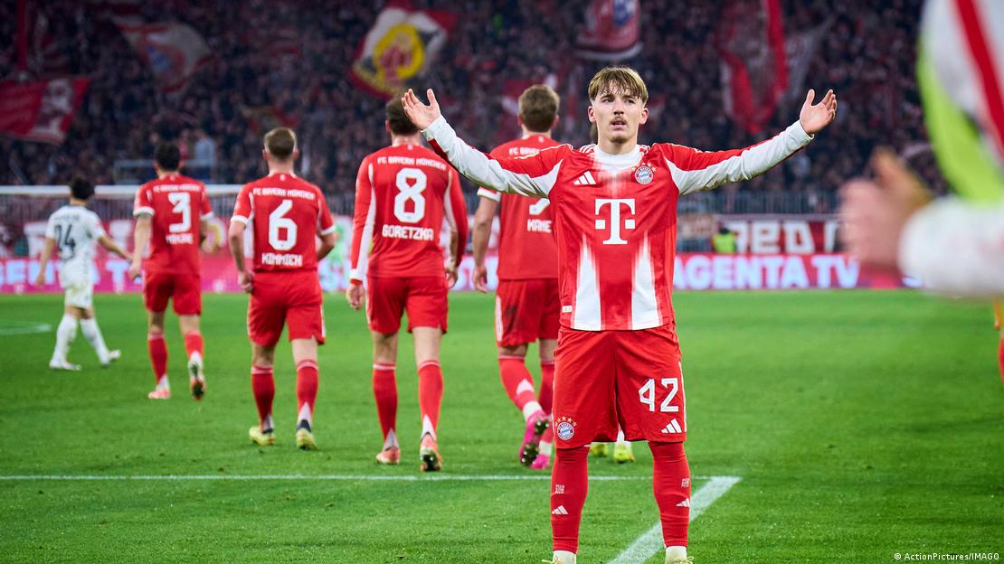 Lennart Karl, de 18 años, abre los brazos en la cancha frente a la cámara celebrando su gol de 1-0. Detrás, sus compañeros del Bayern Múnich caminan de espaldas.