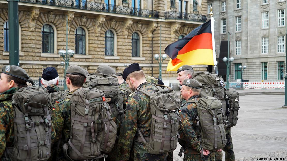 Alman askerleri arkadan görülüyor, bir askerin elinde Alman bayrağı dalgalanıyor