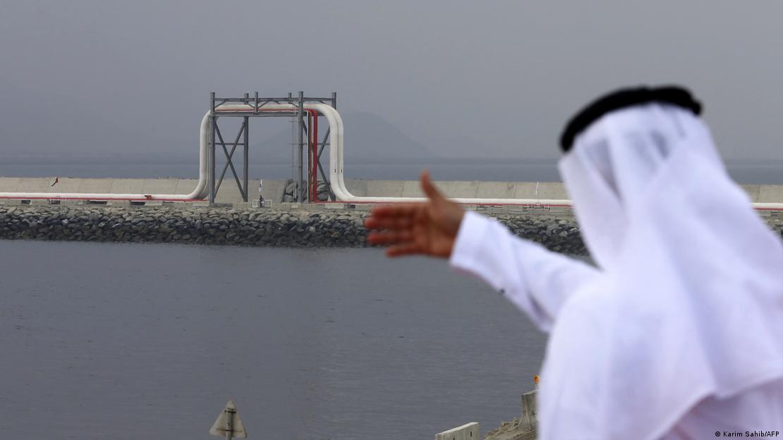 Homem com vestimentas árabes olha para oleoduto