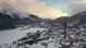 Aerial view of a snow-covered Alpine town featuring a dense historic town center, a tall church tower, a frozen lake, and surrounding mountain ranges in winter. Snow blankets rooftops, streets, and forests, while alpine peaks rise in the background beneath a cloudy sky. Aerial view of a snow-covered Alpine town featuring a dense historic town center, a tall church tower, a frozen lake, and surrounding mountain ranges in winter. Snow blankets rooftops, streets, and forests, while alpine peaks rise in the background beneath a cloudy sky.