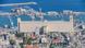 A row of large cranes and a large grey building line the harbor of Haifa A row of large cranes and a large grey building line the harbor of Haifa