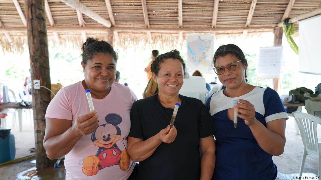 Mulheres seguram recipientes com água do rio