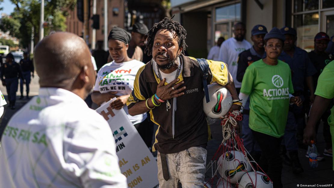 A street vendor gestures as he tries to persuade a protester of his South African citizenship during a protest march against undocumented migrants A street vendor gestures as he tries to persuade a protester of his South African citizenship during a protest march against undocumented migrants