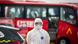 A man stands in front of a red bus in hazmat suit and mask A man stands in front of a red bus in hazmat suit and mask