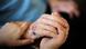 A hospice care worker holds the hand of an elderly person A hospice care worker holds the hand of an elderly person
