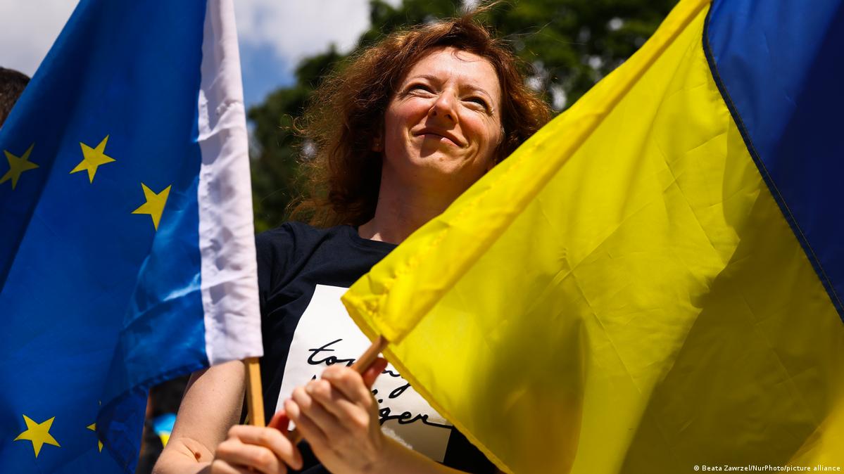 Polen Krakau 2022 | Eröffnung des Platzes der Freien Ukraine neben der russischen Botschaft 2022年7月12日,在波兰克拉科夫原俄罗斯大使馆旁的“自由广场”上,一名女子手持乌克兰国旗和欧盟旗。