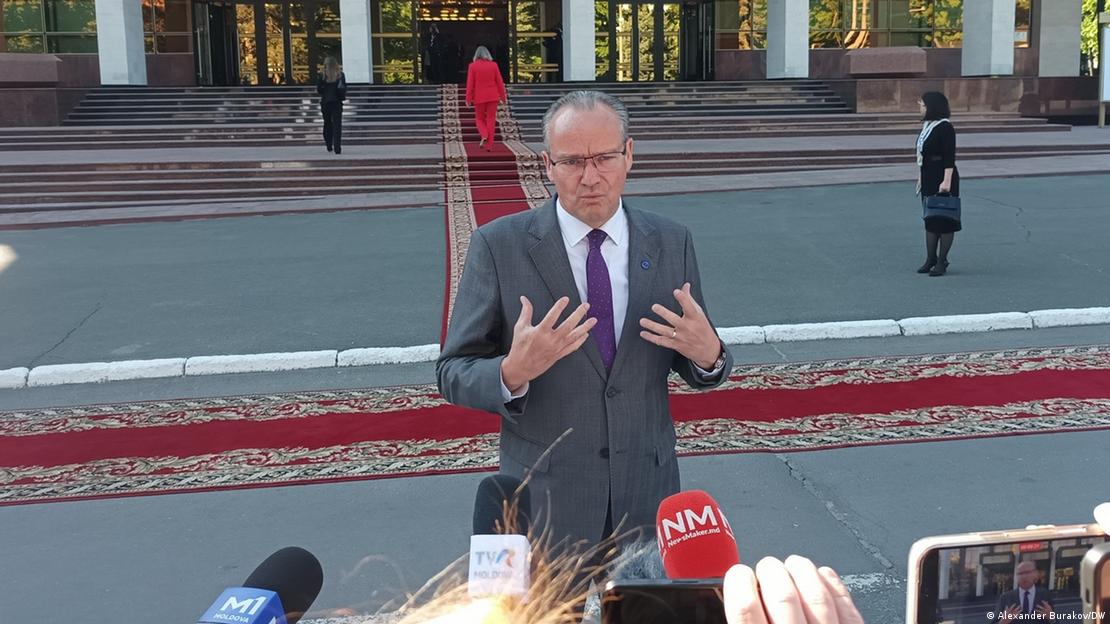 Günther Krichbaum para një ndërtese zyrtare duke folur para gazetarëve. Pas tij është tapeti i kuq, 