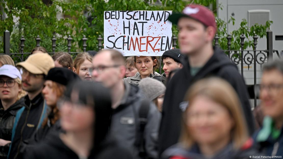 Würzburg'da Almanya Başbakanı Merz'in protesto edildiği eyleme katılan bir göstericinin elindeki dövizde "Deutschland hat schMERZen" (Almanya'nın ağrılar var) yazıyor.