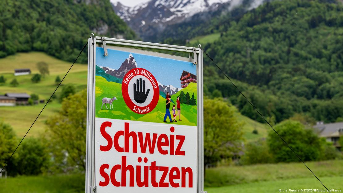 Cartaz da campanha "Não à Suíça de dez milhões" mostra paisagem alpina e a frase "Proteja a Suíça". Cartaz da campanha "Não à Suíça de dez milhões" mostra paisagem alpina e a frase "Proteja a Suíça".