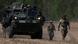 US soldiers walking by military vehicle along dirt track in Bemowo Piskie, Poland, during NATO drill US soldiers walking by military vehicle along dirt track in Bemowo Piskie, Poland, during NATO drill