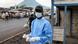 A masked healthcare worker holds thermometers at a checkpoint near Goma, DRC, as a crowd can be seen behind him A masked healthcare worker holds thermometers at a checkpoint near Goma, DRC, as a crowd can be seen behind him