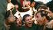 Film still from 'Coward': A group of young men in World War I uniforms cheering and hugging each other. Film still from 'Coward': A group of young men in World War I uniforms cheering and hugging each other.