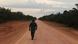 A man walks down an unpaved stretch of BR-319 highway A man walks down an unpaved stretch of BR-319 highway
