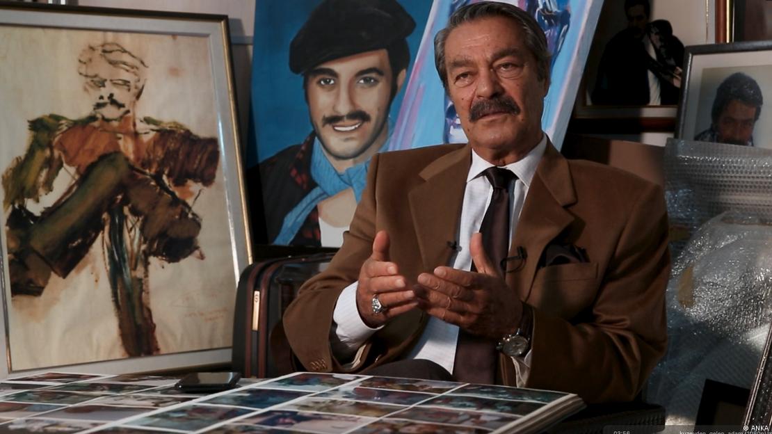Kadir İnanır bir röportaj esnasında konuşuyor. Önünde eski fotoğraflar, arkasında ise yağlı boya portreleri var.