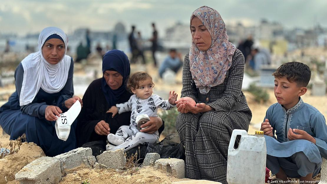 Gazze'de ölen yakınlarının mezarlarını bayram nedeniyle ziyaret eden Filistinliler. Kadın ve çocuklar dua ediyor