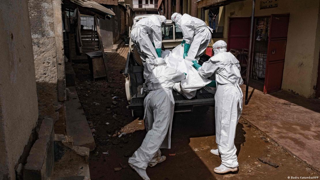 Cuatro trabajadores con trajes protectores trasladan el cadáver de una persona fallecida presuntamente a causa de la cepa Bundibugyo del virus del Ébola en Uganda. (26.05.2026).