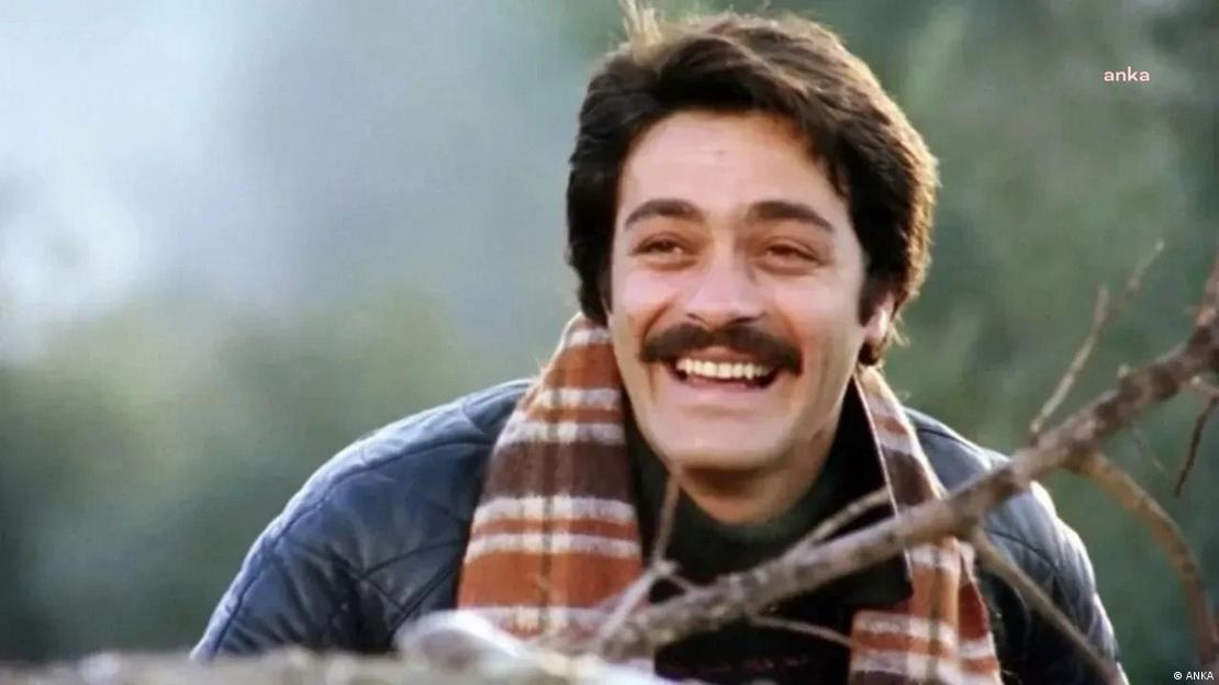 "Selvi Boylum Al Yazmalım" filminden bir sahnede bir ağaç dalının arkasından gülümseyen Kadir İnanır