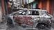 Carro queimado com a pichação "organize seu ódio"