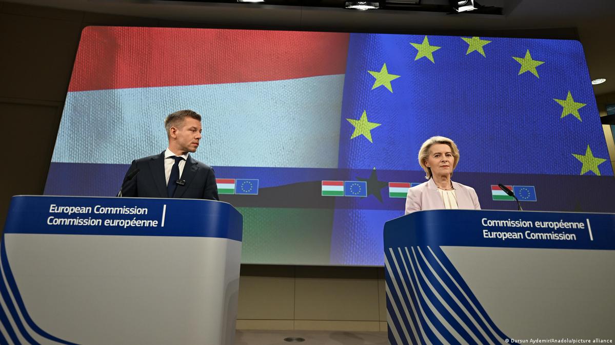 Hungarian Prime Minister Peter Magyar and European Commission President Ursula von der Leyen are standing at podiums during a press conference in Brussels, with Hungarian and EU flag in background
