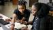 Two women collaborate on computers.