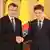 Doi bărbați își strâng mâinile în fața drapelelor României, UE și NATO: președintele Nicușor Dan (dreapta) și premierul desemnat Euugen Tomac