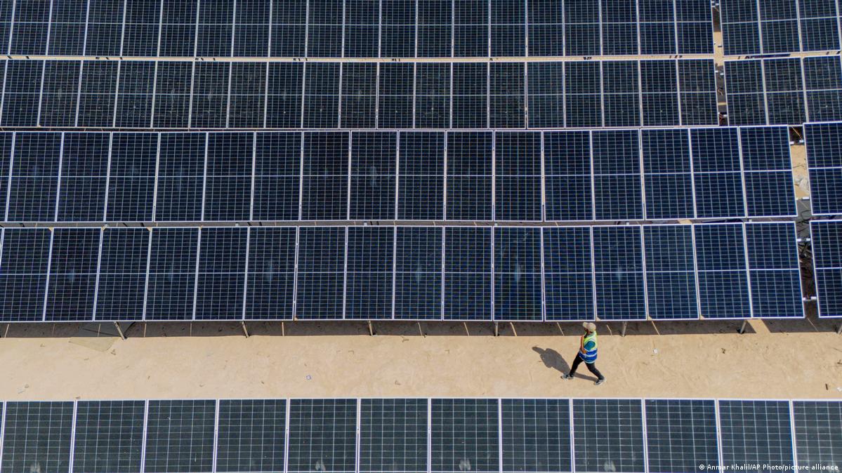 A worker walks past rows of panels at a newly opened industrial-scale solar power plant in Karbala, Iraq, Wednesday, Sept. 17, 2025. Seen from above