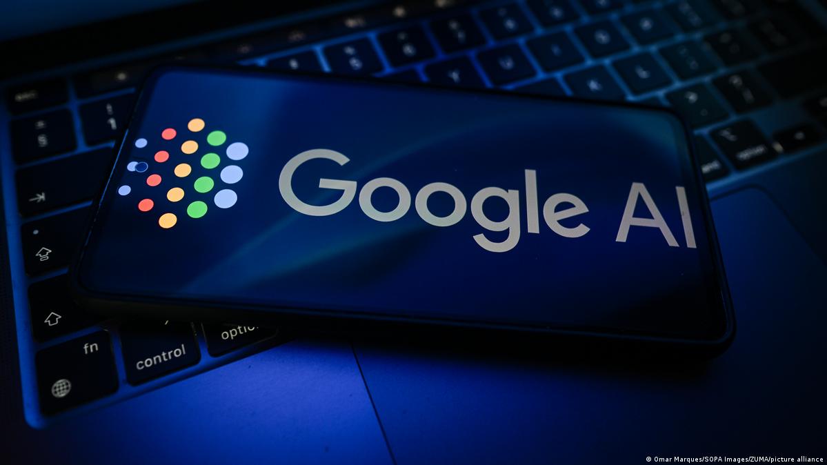 A Google AI logo is seen displayed on a smartphone on the top of a laptop