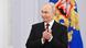 O presidente da Rússia, Vladimir Putin, veste terno escuro, gravata bordô e camisa branca, e aparece sorrindo e aplaudindo.