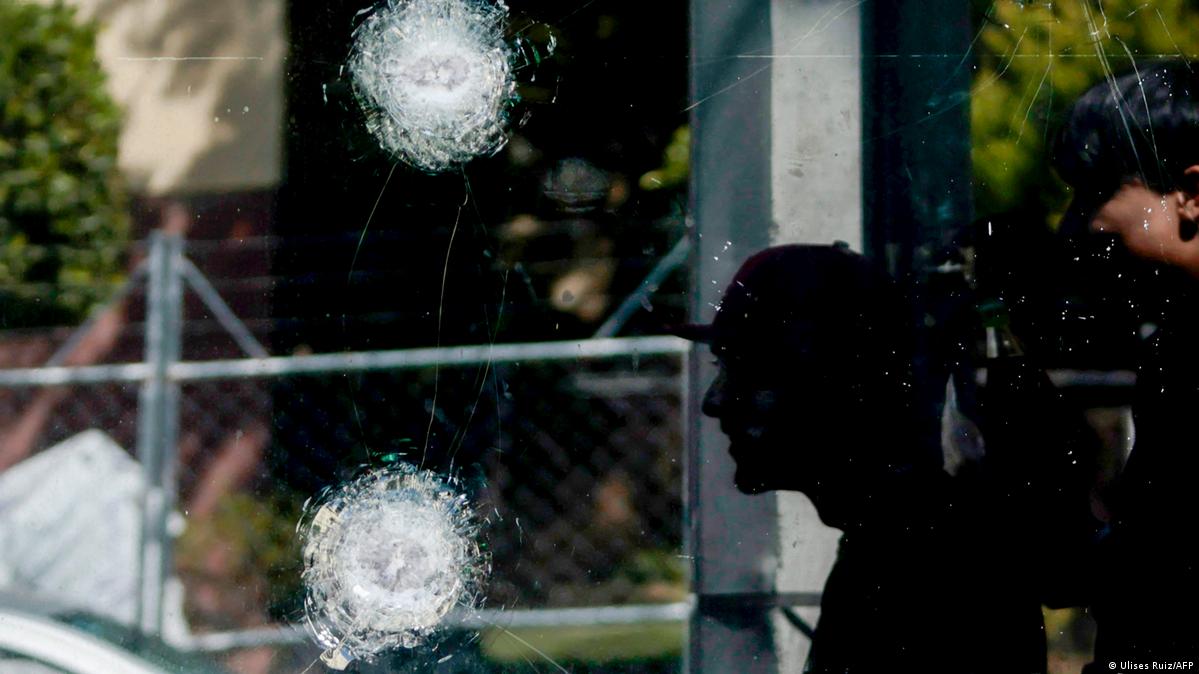 Young men walk past the window of a police station with bullet impacts in Guadalajara, Jalisco, Mexico, on February 23, 2026