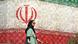 Frau vor Plakatwand mit iranischer Nationalflagge Frau vor Plakatwand mit iranischer Nationalflagge