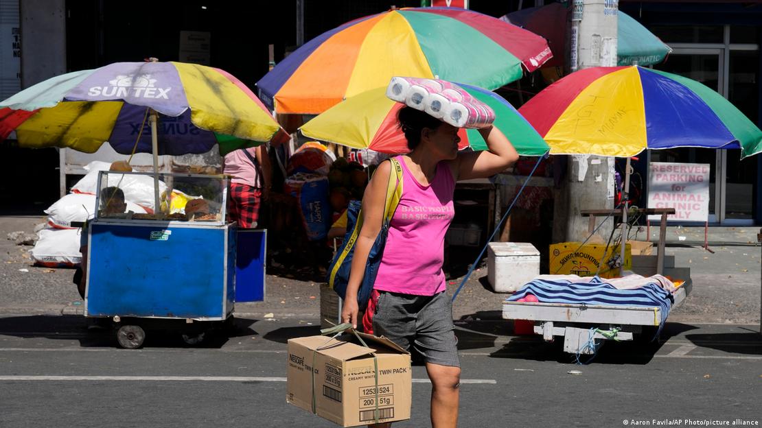 Quezon City, Filipinas: una mujer se protege del sol con un paquete de rollos de papel. Quezon City, Filipinas: una mujer se protege del sol con un paquete de rollos de papel.