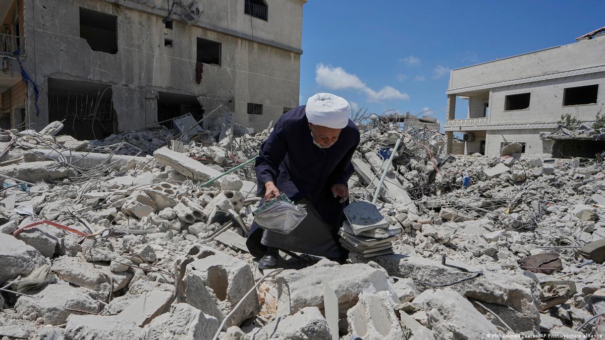 A Shiite sheikh who returns to his village following the announcement of an initial ceasefire agreement between the United States and Iran, collects religious books from his destroyed library in Deir 