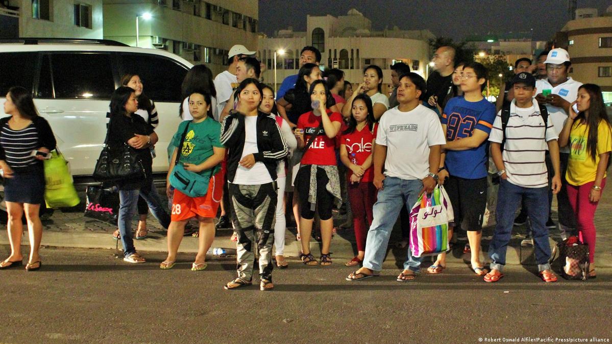 Filipino guest workers wait for transport on the side of the road in Dubai (24.11.2015)