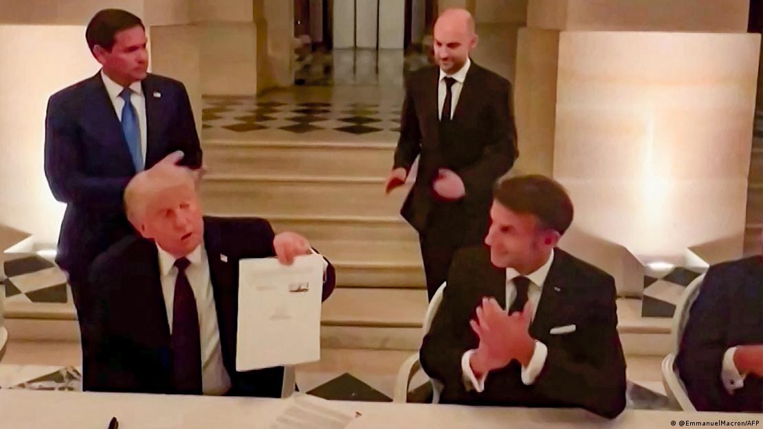 ABD Başkanı Donald Trump, Versay Sarayı'nda Fransa Cumhurbaşkanı Emmanuel Macron'un ev sahipliği yaptığı yemekte imzaladığı mutabakat zaptını havaya kaldırarak gösteriyor. ABD Başkanı Donald Trump, Versay Sarayı'nda Fransa Cumhurbaşkanı Emmanuel Macron'un ev sahipliği yaptığı yemekte imzaladığı mutabakat zaptını havaya kaldırarak gösteriyor.
