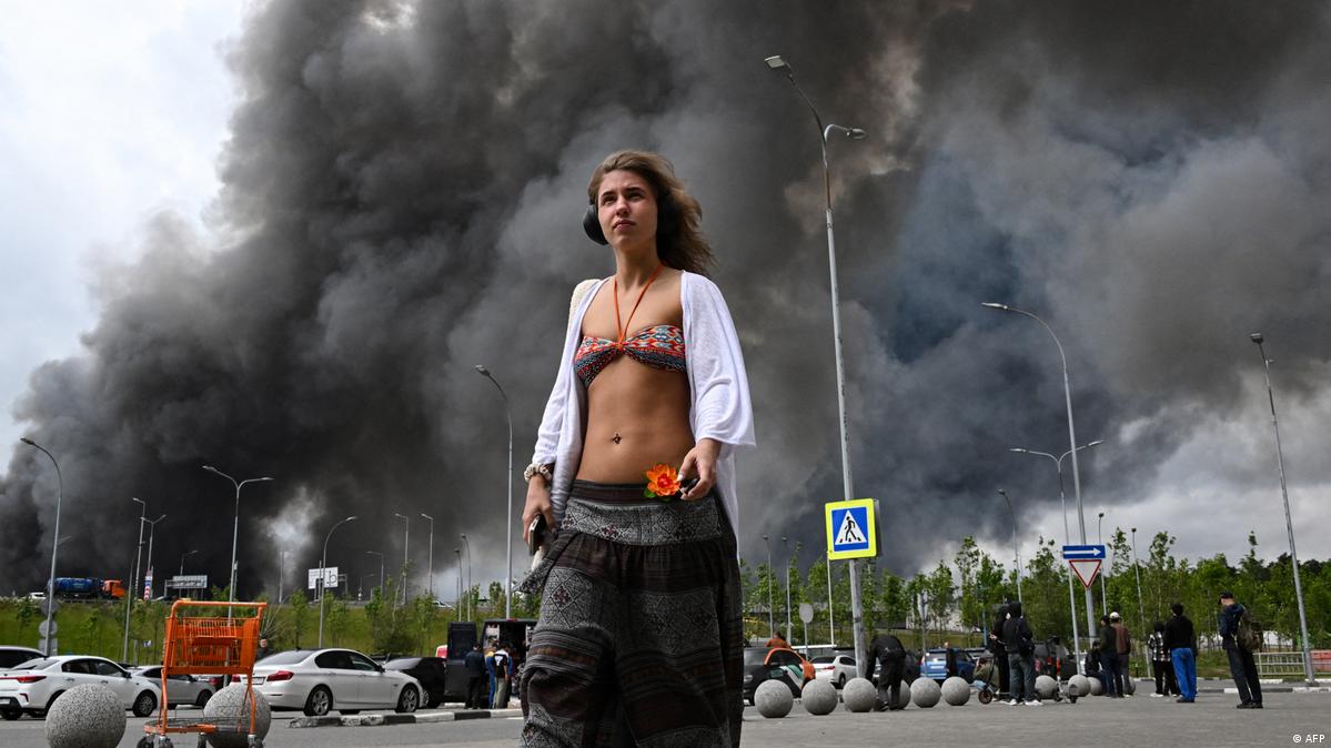 Russland Moskau 2026 | Frau vor Einkaufszentrum mit Rauch über Gazprom-Neft-Raffinerie 无人机袭击中,莫斯科炼油厂、民宅和购物中心受损