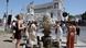 A crowd gathers to drink water at a Roman fountain