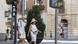 Tourists pass by a thermometer reading 39 degrees Celsius