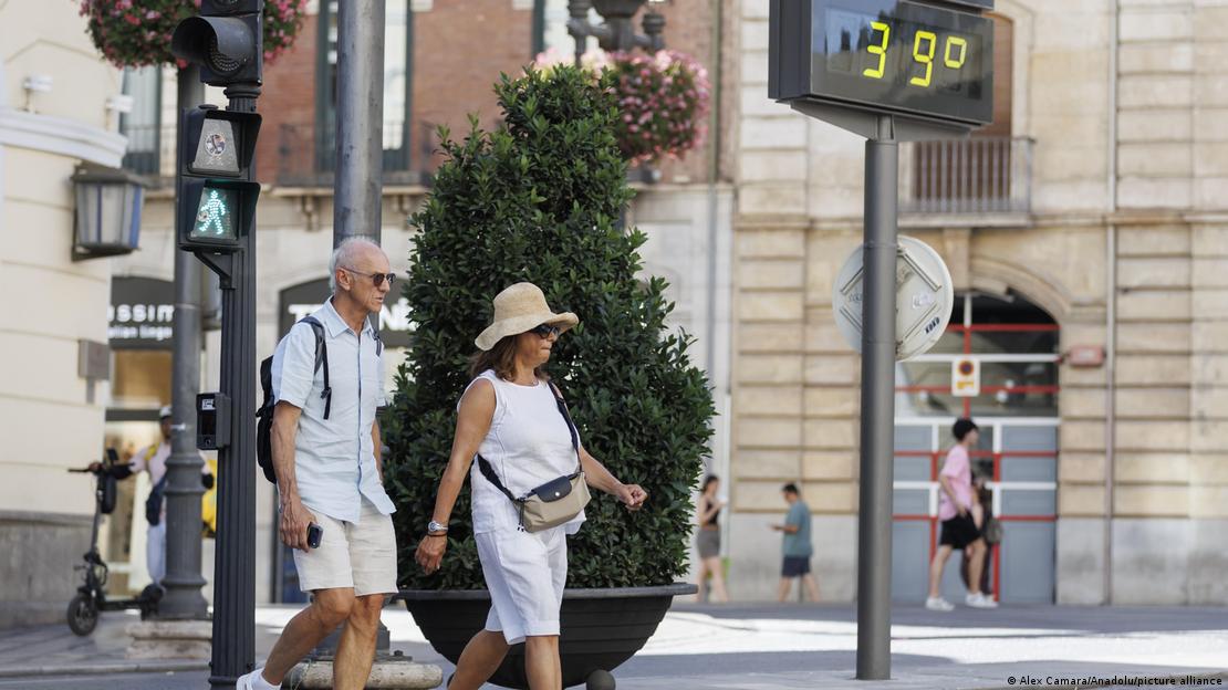 Tourists pass by a thermometer reading 39 degrees Celsius Tourists pass by a thermometer reading 39 degrees Celsius
