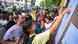 Students arrive at an examination centre and point at a board Students arrive at an examination centre and point at a board