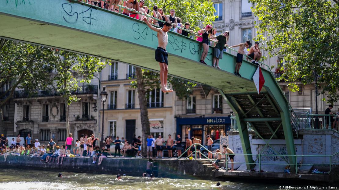 Para combatir las altas temperaturas, un grupo de jóvenes se reúnen en una pasarela antes de lanzarse al canal Saint-Martin en París (22.06.2026)