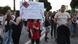 Environmental activists, families, members of the Albanian diaspora, tourists and young people participate in a demonstration in Tirana, Albania, on June 14, 2026. The child in the middle is wearing a T-shirt in the design of the Albanian flag and holds up a placard that reads 'Mornings are for [gaming] and afternoons are for Flamingo Revolution'