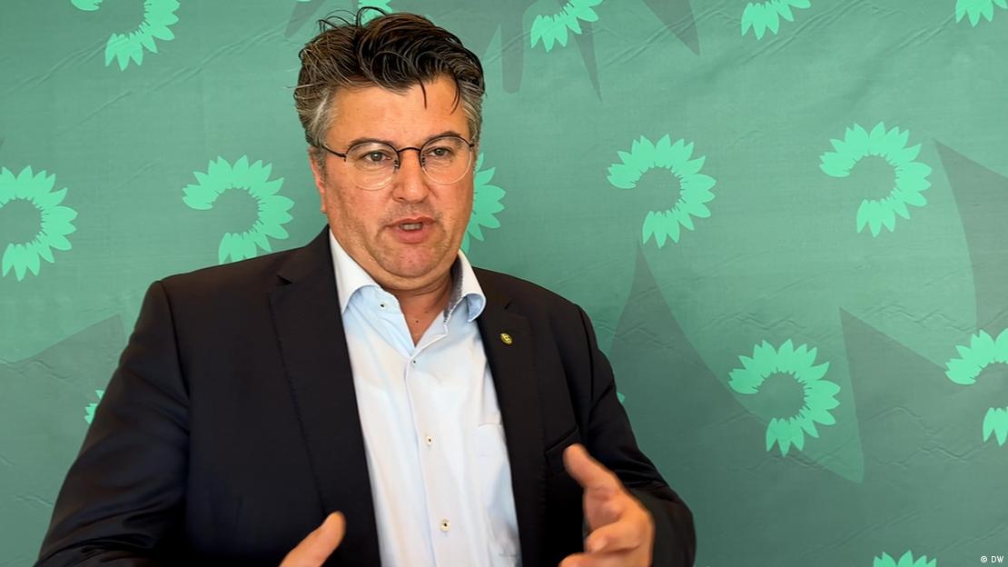 Boris Mijatović duke folur gjatë një interviste për DW, përpara një muri me logon e partisë Aleanca 90/Të Gjelbrit.