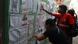Pessoas olhando mural com listas Pessoas olhando mural com listas