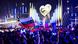 A crowd waves flags in front of a stage that has an illuminated heart on it A crowd waves flags in front of a stage that has an illuminated heart on it