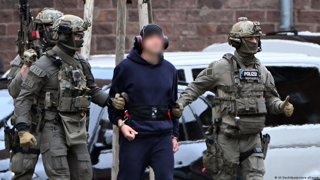 Una persona está siendo conducida por militares a un helicóptero.