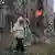Una señora camina frente a un edificio en llamas
