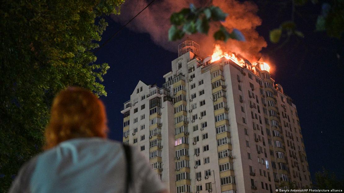 Una mujer observa un edificio en llamas en Kiev.