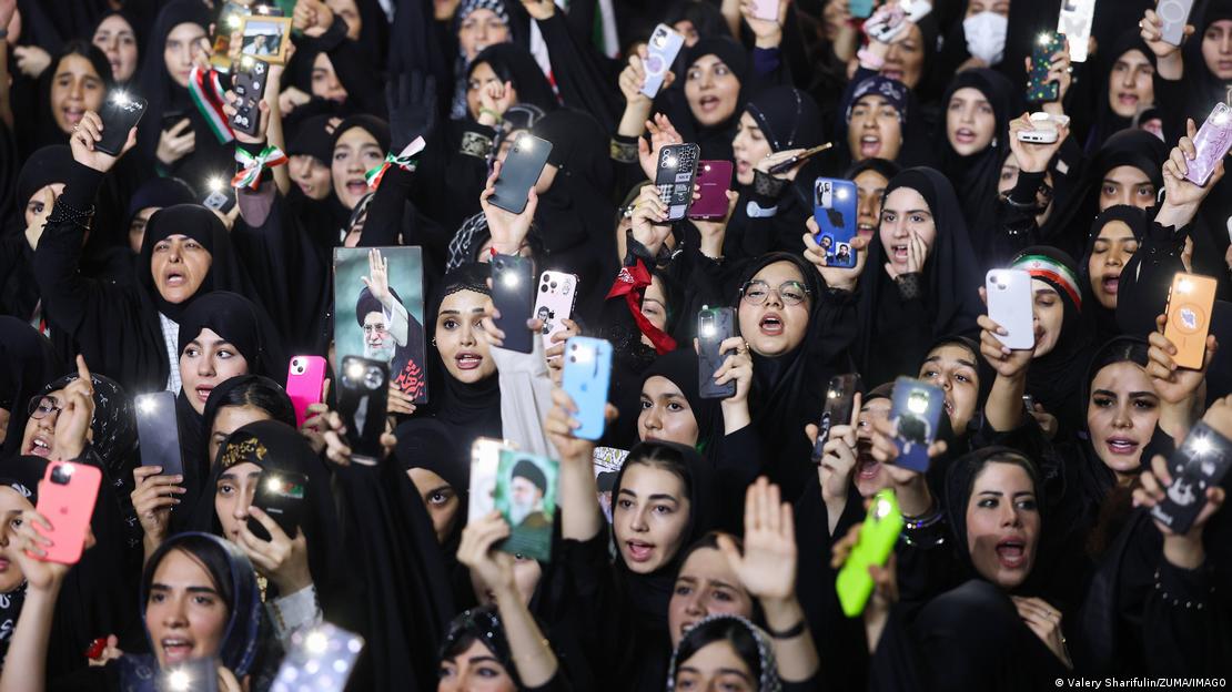 Mulheres levantam fotos de Ali Khamenei e celulares durante cerimônia de homenagem ao líder supremo falecido
